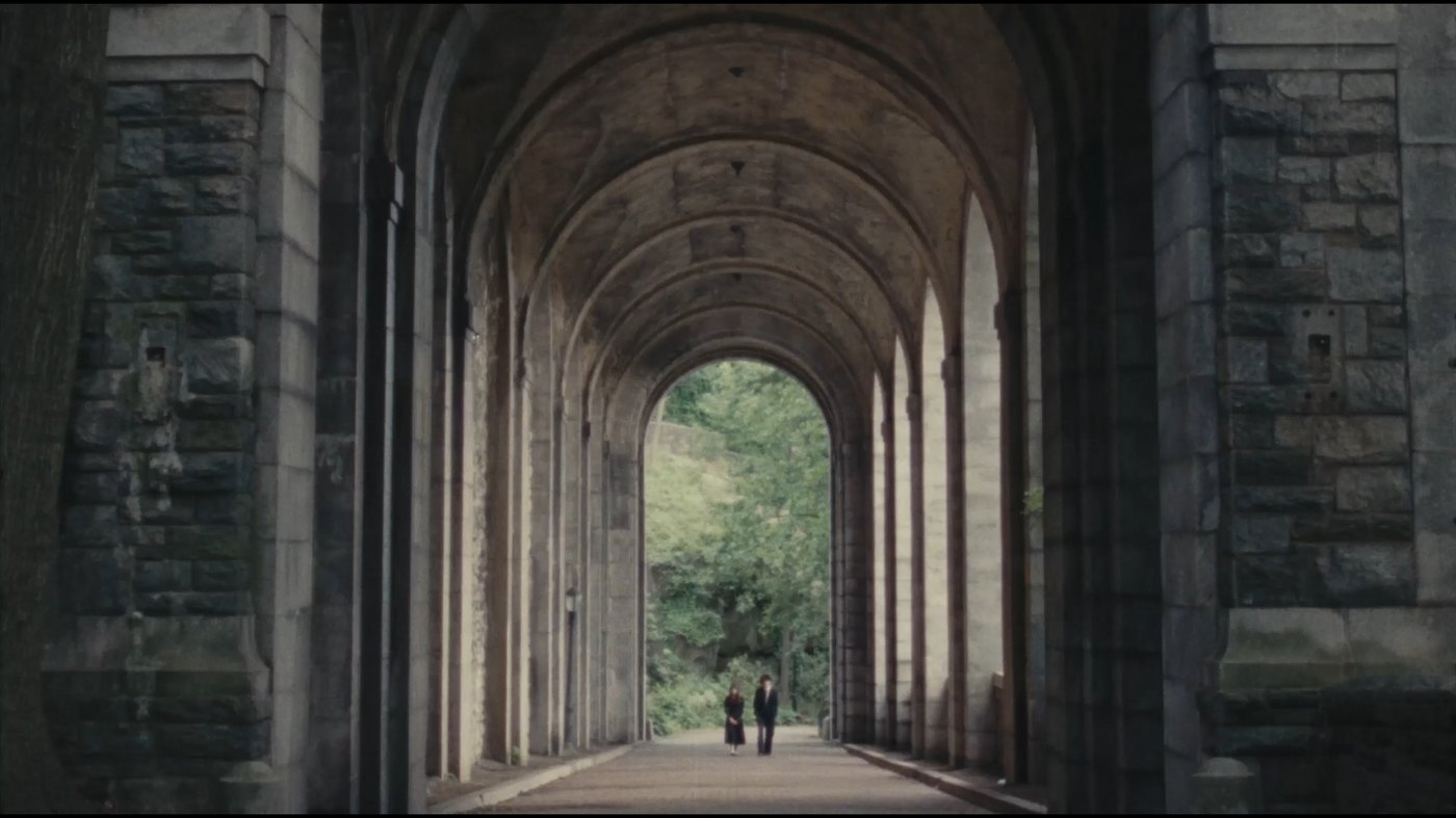 Two small figures walk beneath the vaulted stone arcade at Fort Tryon